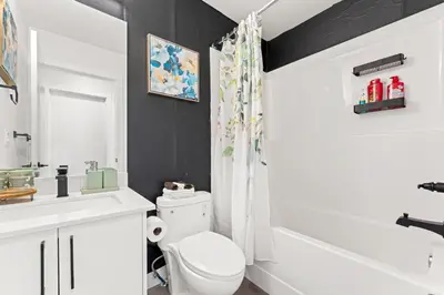 a bathroom with a white toilet and a sink at Modern garden suite with parking in Edmonton