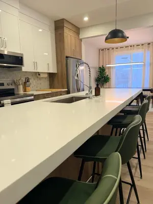 a kitchen with a white counter and green chairs at Cozy and Family-friendly Newly built 3BR Home in Chestermere
