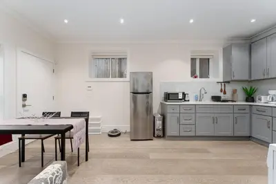 a kitchen with a table and a stainless steel refrigerator at New Modern 2BR Suite near UBC Pacific Spirit Park in Vancouver