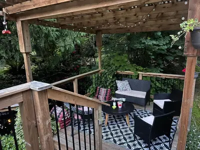 a wooden pergola with chairs and a table on a deck at Ships Point Wellness INC in Fanny Bay