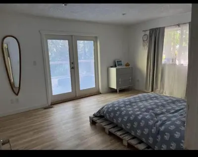 a bedroom with a bed and a dresser and a mirror at Ships Point Wellness INC in Fanny Bay