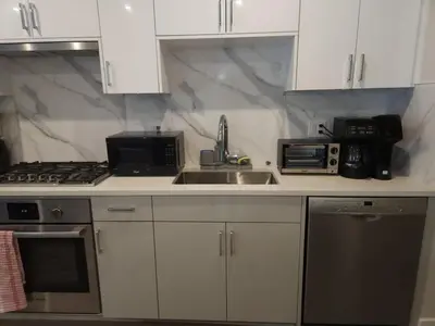a kitchen with white cabinets and a sink and a microwave at Vancouver Family Condo 2 Bedrooms 2 Baths Near UBC & Parks in Vancouver
