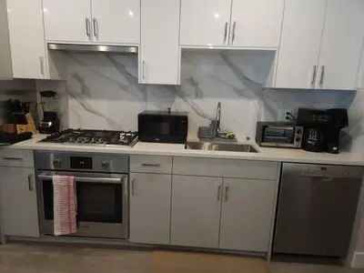 a kitchen with white cabinets and a stove and a sink at Vancouver Townhouse 2 Queen Beds Kitchen Street Parking - Perfect for Families in Vancouver