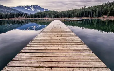 a wooden dock on a lake with a mountain at The Alpine Alcove w Pool & Hot Tub in Whistler