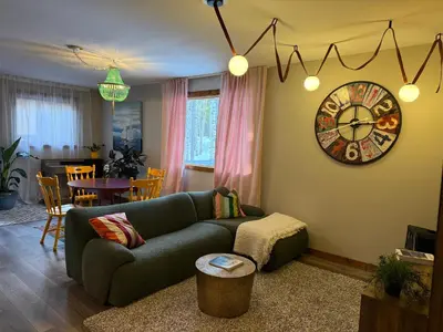 a living room with a couch and a clock on the wall at Bragg Creek Vacation Estate with hot tub, sauna, pool table, karaoke, private pond and forest trails in Bragg Creek