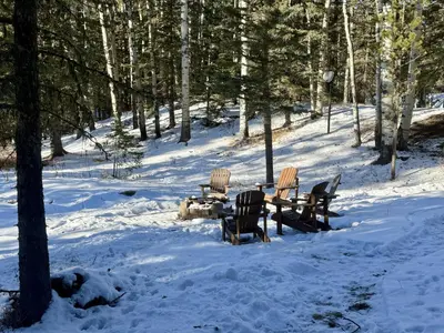 a group of chairs sitting around a table in the snow at Bragg Creek Vacation Estate with hot tub, sauna, pool table, karaoke, private pond and forest trails in Bragg Creek