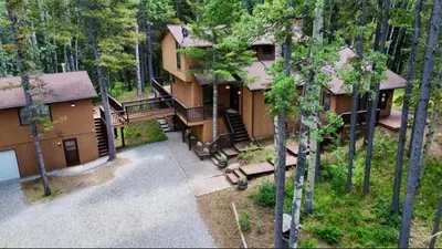 an aerial view of a house in the woods at Bragg Creek Vacation Estate with hot tub, sauna, pool table, karaoke, private pond and forest trails in Bragg Creek