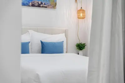 a bedroom with a white bed with blue pillows at NEW Cambie Village 2 Bed Suite Near Skytrain in Vancouver