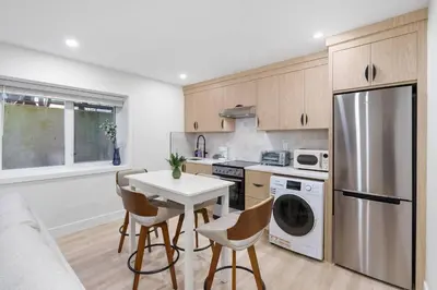 a kitchen with a white table and chairs and a refrigerator at NEW Cambie Village 2 Bed Suite Near Skytrain in Vancouver
