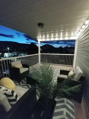 a porch with a couch and chairs on a balcony at Modern Lake City Getaway in Penticton