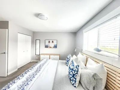 a bedroom with a large bed with blue and white pillows at Modern Lake City Getaway in Penticton