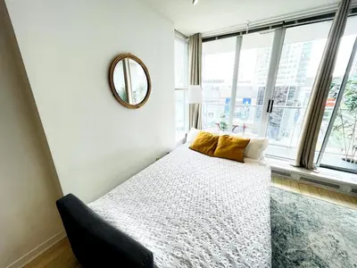 a bedroom with a bed and a mirror on the wall at Downtown Suite with Parking, Pool, Gym in Vancouver