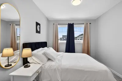 a bedroom with a white bed and a mirror at modern 3bedroom space sleeps 6 free parking in Edmonton