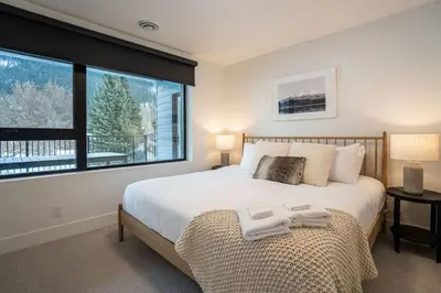 a bedroom with a bed and a large window at Qs Hideaway in Mackenzie Village in Revelstoke