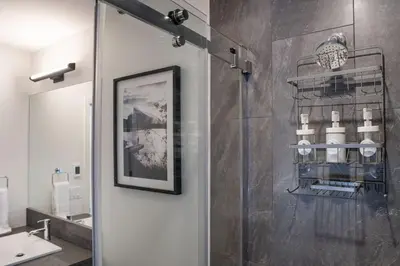 a bathroom with a shower with a sink and a mirror at The Peaks and Birdies in Mackenzie Village, Revelstoke in Revelstoke