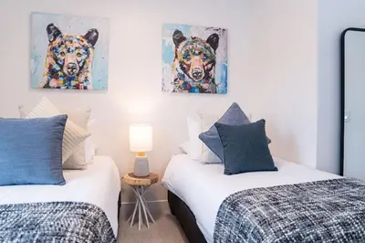 two beds in a bedroom with two paintings of dogs at Bluebird Daze in Mackenzie Village in Revelstoke