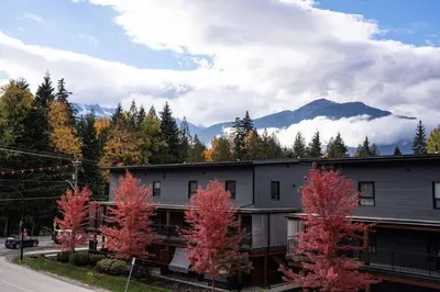a building with red trees and mountains in the background at Bluebird Daze in Mackenzie Village in Revelstoke