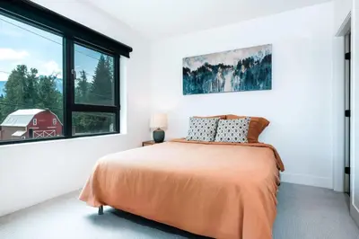 a bedroom with a bed and a window and a red barn at Alpine Ascent with Hot Tub in Mackenzie Village in Revelstoke