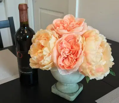 a vase filled with pink flowers next to a bottle of wine at EVE'S Room Connect YVR Downtown UBC in Vancouver