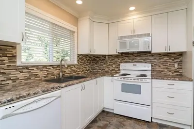 a kitchen with white cabinets and a sink and microwave at Quiet Furnished Room Near Transit and Hospital long stays in Surrey