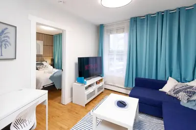 a living room with a blue couch and a tv at Quiet & Walkable - Stampede, BMO, Nightlife & Eats in Calgary
