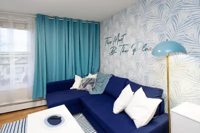 a blue couch in a living room with a blue curtain at Quiet & Walkable - Stampede, BMO, Nightlife & Eats in Calgary