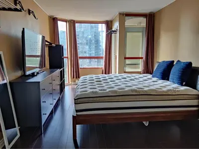 a bedroom with a bed with blue pillows and a television at Comfortable 2-Bedroom Downtown Stay Prime Area in Vancouver