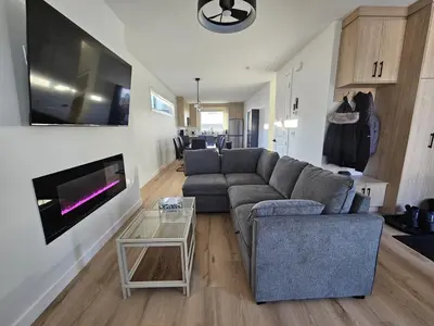 a living room with a couch and a tv at Shaganappi 2BR with private Baths, Walk to CTrain, Garage Parking, Full Kitchen in Calgary