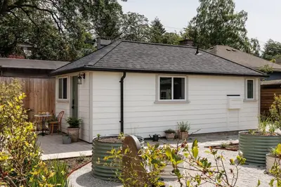 a small white house with a patio and plants at The Garden Studio in Victoria