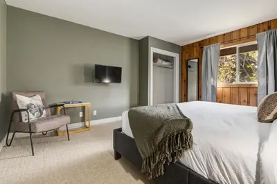 a bedroom with a bed and a chair and a television at 2BR Red Cedar Lodge near Banff with Mountain Views in Canmore
