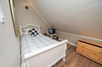 a small bedroom with a white bed in a attic at 3BR Oasis Private Hot Tub and Sauna Walk to Ski Hill in Kimberley