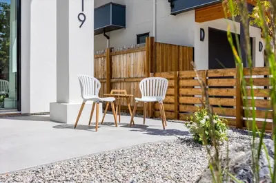 two chairs and a table in front of a house at Luxurious 4BR Beach Retreat with Backyard and Balcony in Penticton