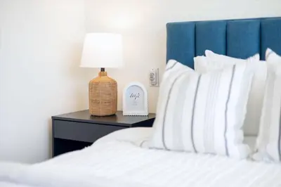 a bed with a blue headboard and a lamp on a table at Luxurious 4BR Beach Retreat with Backyard and Balcony in Penticton