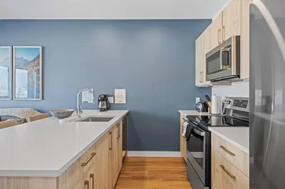 a kitchen with blue walls and wooden cabinets at Cozy 2BR apartment in Golden near DT in Golden