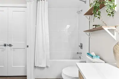 a bathroom with a white shower curtain and a toilet at Luxe 3BR Golden Hideaway Top Floor, Balcony & BBQ in Golden