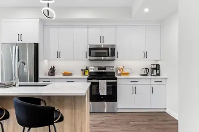 a white kitchen with a stove and a microwave at Scenic Riverstone 2BR w/ Balcony + BBQ, Sleeps 6! in Golden