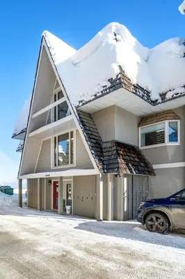 a snow covered house with a car parked in front at Charming 1BR Near DT Kimberley: Pool, Hot Tub, Gym in Kimberley
