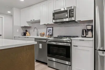 a kitchen with stainless steel appliances and white cabinets at Brand New 3BR Rockies Haven w/ Balcony, Pool & Gym in Dead Man's Flats