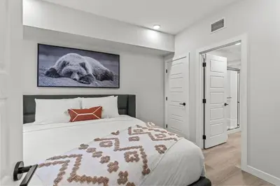a bedroom with a bed with a picture on the wall at Brand New 3BR Rockies Haven w/ Balcony, Pool & Gym in Dead Man's Flats