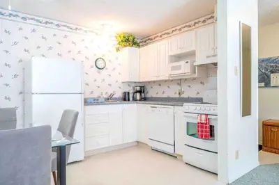 a kitchen with white cabinets and a white refrigerator at Kimberley Escape: 1BR+Studio w/ Hot Tub, Pool, BBQ in Kimberley