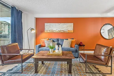 a living room with orange walls and a blue couch at Stampede Modern downtown Condo Spacious 2BR in Calgary