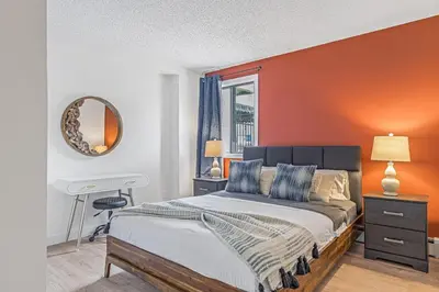 a bedroom with a bed with an orange wall at Stampede Modern downtown Condo Spacious 2BR in Calgary