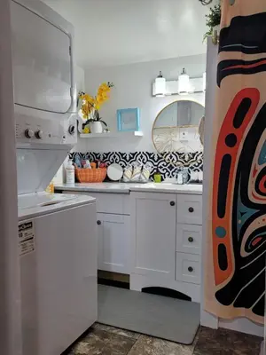 a kitchen with white cabinets and a sink at Nesting Ravens cottage in Nanaimo