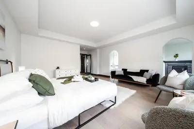 a white bedroom with a large bed and a living room at Luxury Sleeps 10 King bed Jacuzzi 10 Min to West Edmonton Mall in Edmonton