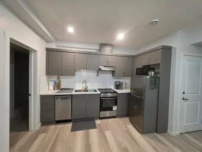 a kitchen with stainless steel appliances and wooden floors at Amaville Suites - One Bedroom in West Edmonton in Edmonton