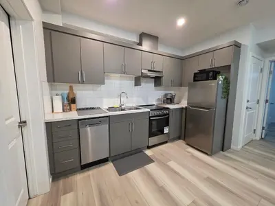 a kitchen with gray cabinets and stainless steel appliances at Amaville Suites - One Bedroom in West Edmonton in Edmonton