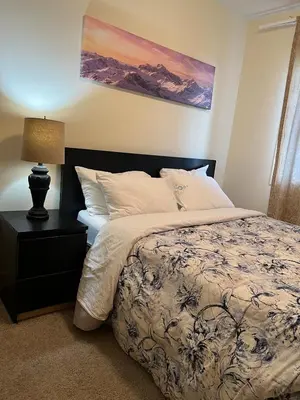 a bedroom with a bed and a lamp on a night stand at Modern Vacation Home Near West Edmonton Mall, Transit Center & LRT - 3BR in Edmonton