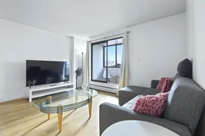 a living room with a couch and a glass table at Bright 2 Bedroom Suite at Victoria & Stampede Park in Calgary
