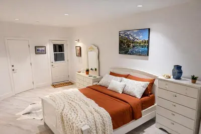 a bedroom with a bed with orange sheets and pillows at Cozy Deep Cove Retreat Near Quarry Rock Hike in North Vancouver