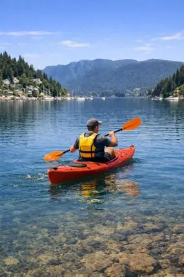 a man in a red kayak on a lake at Cozy Deep Cove Retreat Near Quarry Rock Hike in North Vancouver